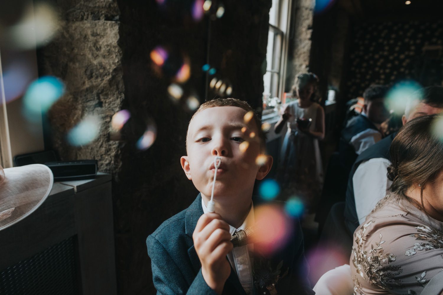 A young boy blows bubbles at the camera