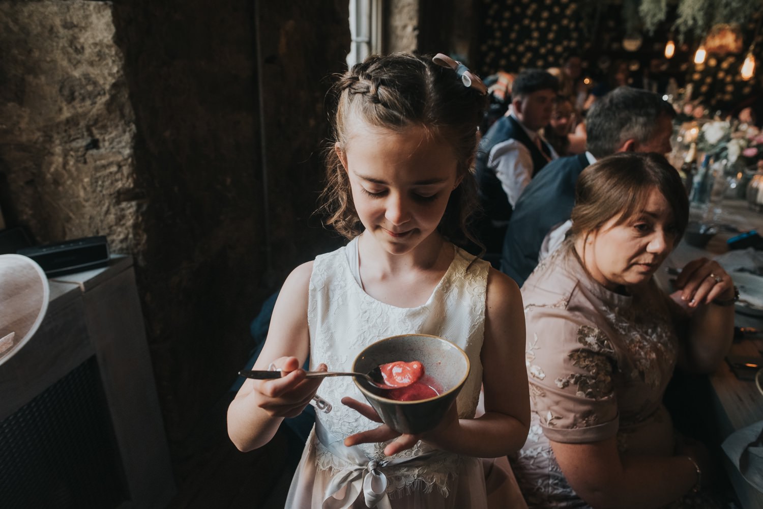 A young girl eats red sorbet from a bowl