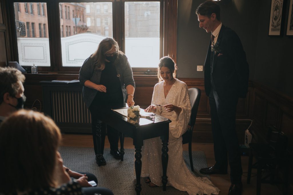 The bride sits down to sign the marriage certificate 