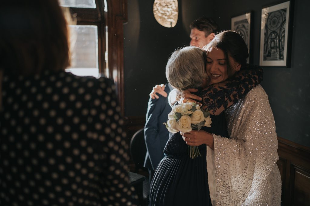 The bride smiles as she hugs her mother