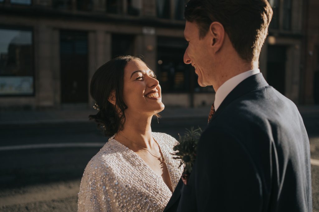 The bride and groom smile at each other in the Glasgow sunlight