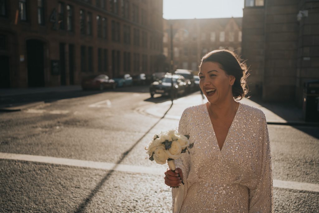 The bride laughs as she walks across the road