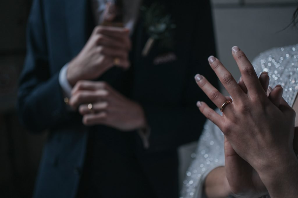 A close up photo of the bride and groom fidgeting with their new wedding rings