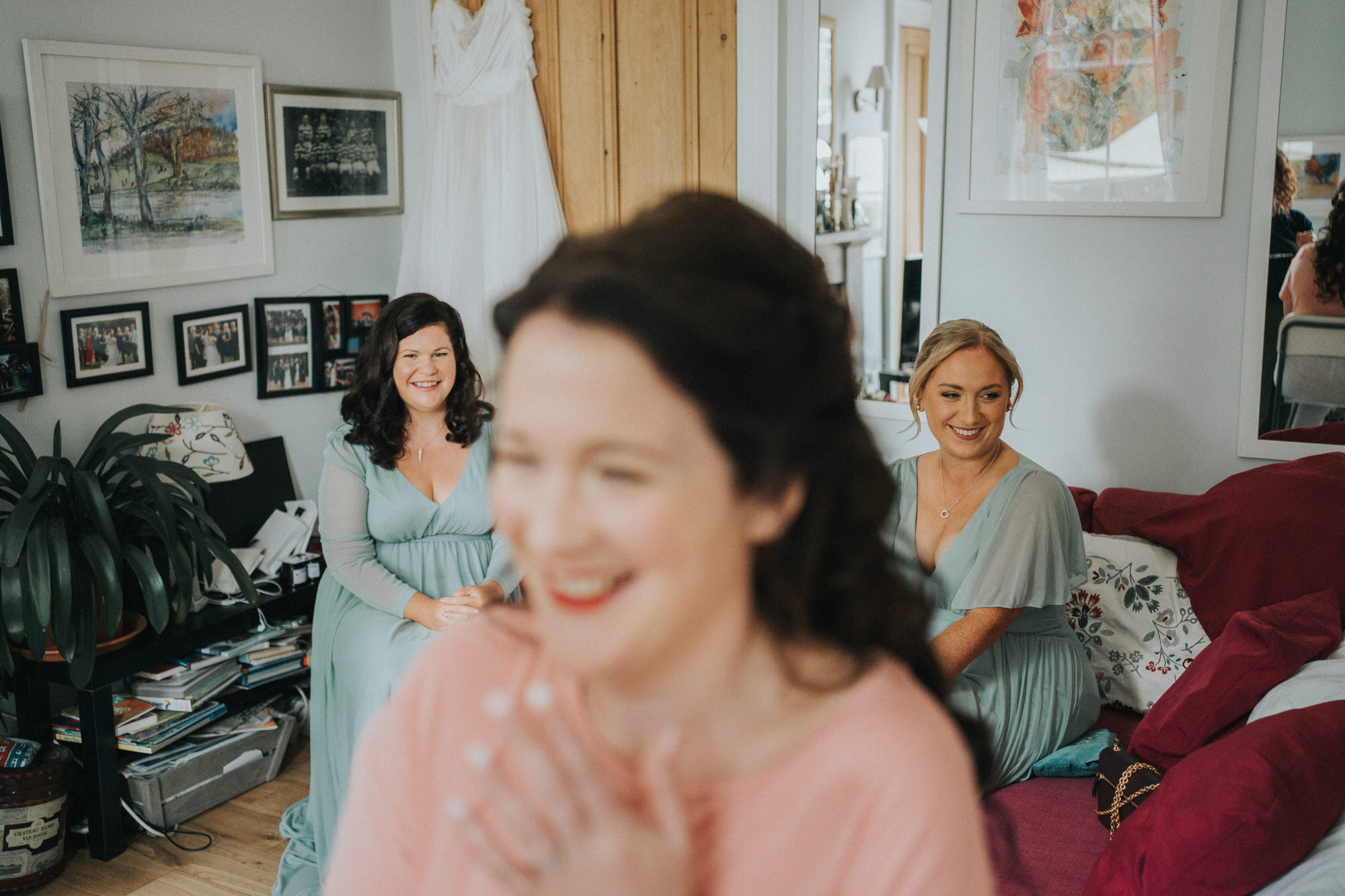 Two bridesmaids sit behind the bride and smiles