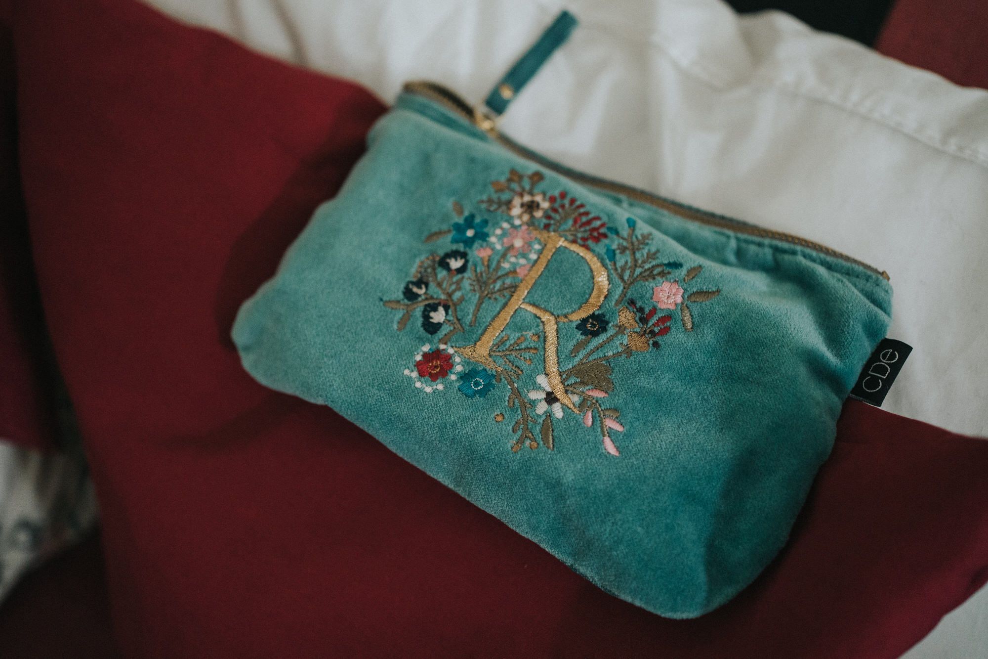 A turquoise purse with an embroidered R on it