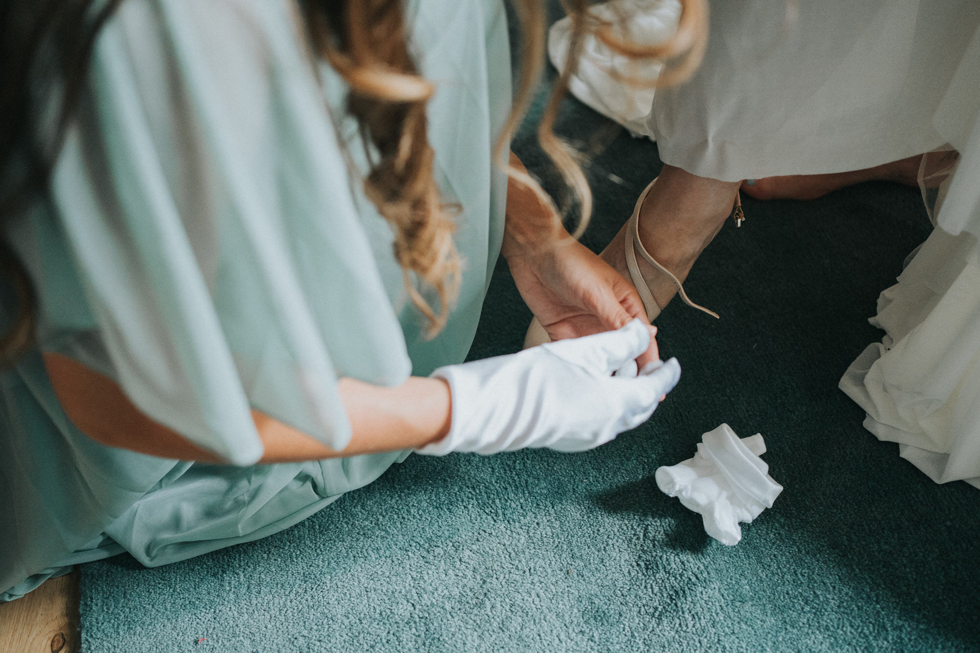 A bridesmaid helps the bride with her shoes