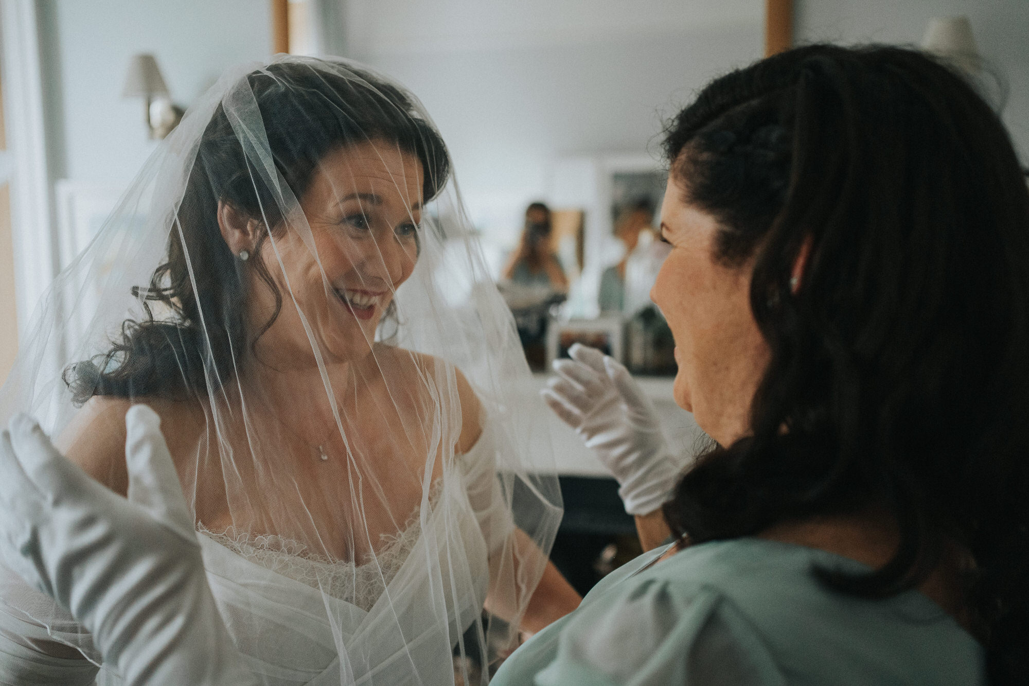 The bride laughs as she puts the veil over her head
