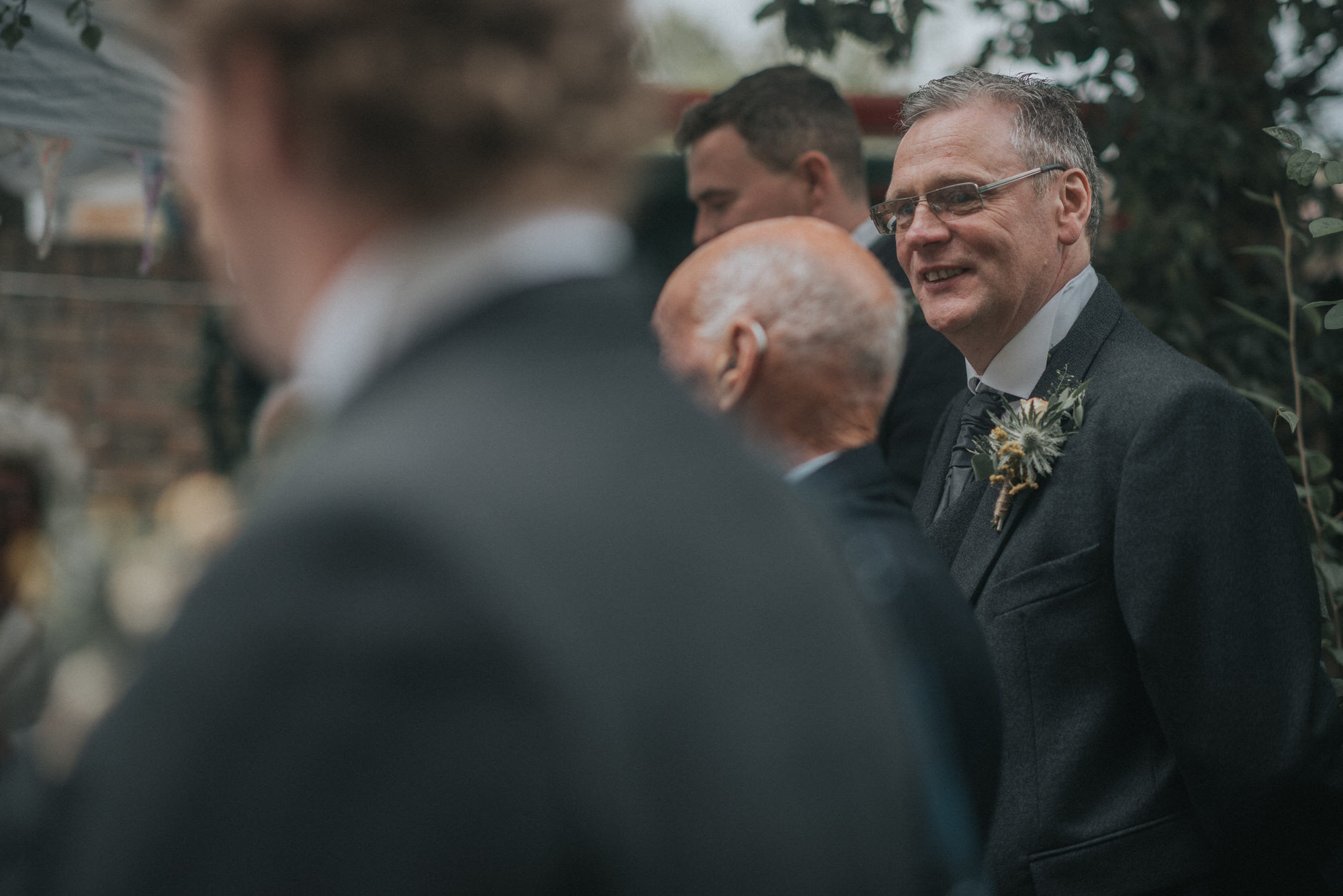 The Grooms Dad smiles and looks at the groom whilst he is giving a speech