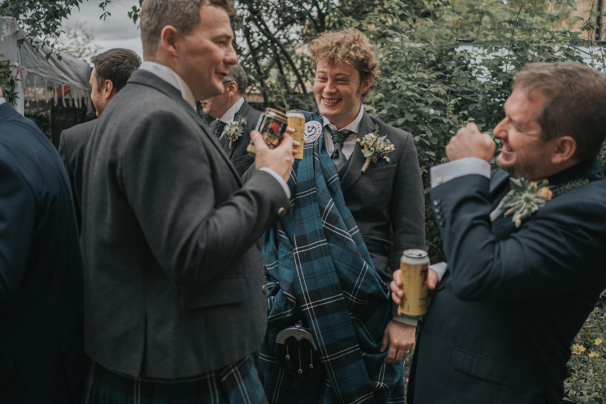 The groom shares a laugh with his guests as they drink Tennents Lager