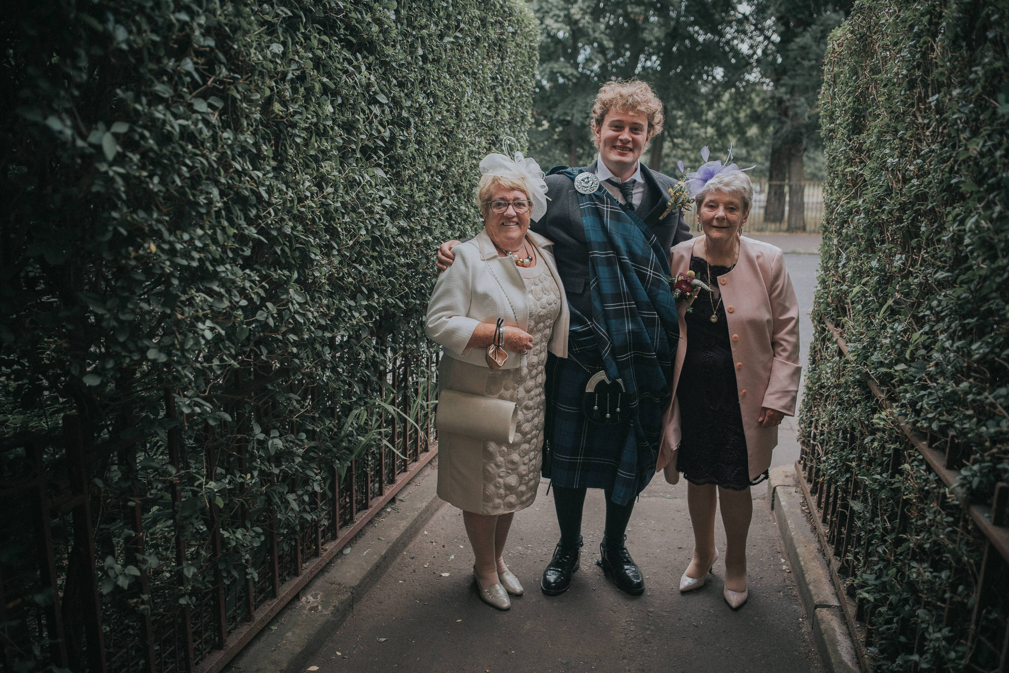A groom stands with his two grannies