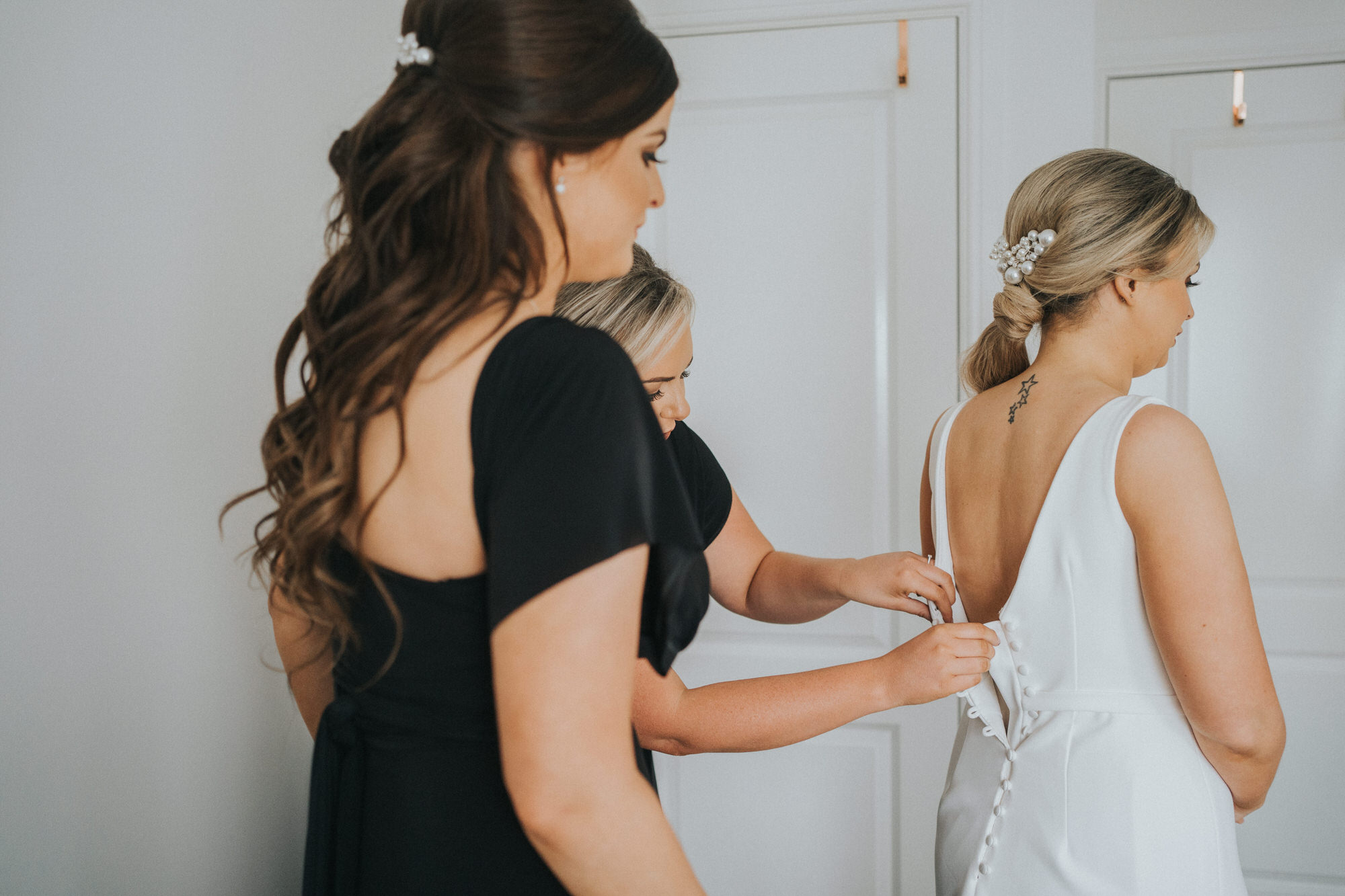 The bride has her dress fixed by her bridesmaids