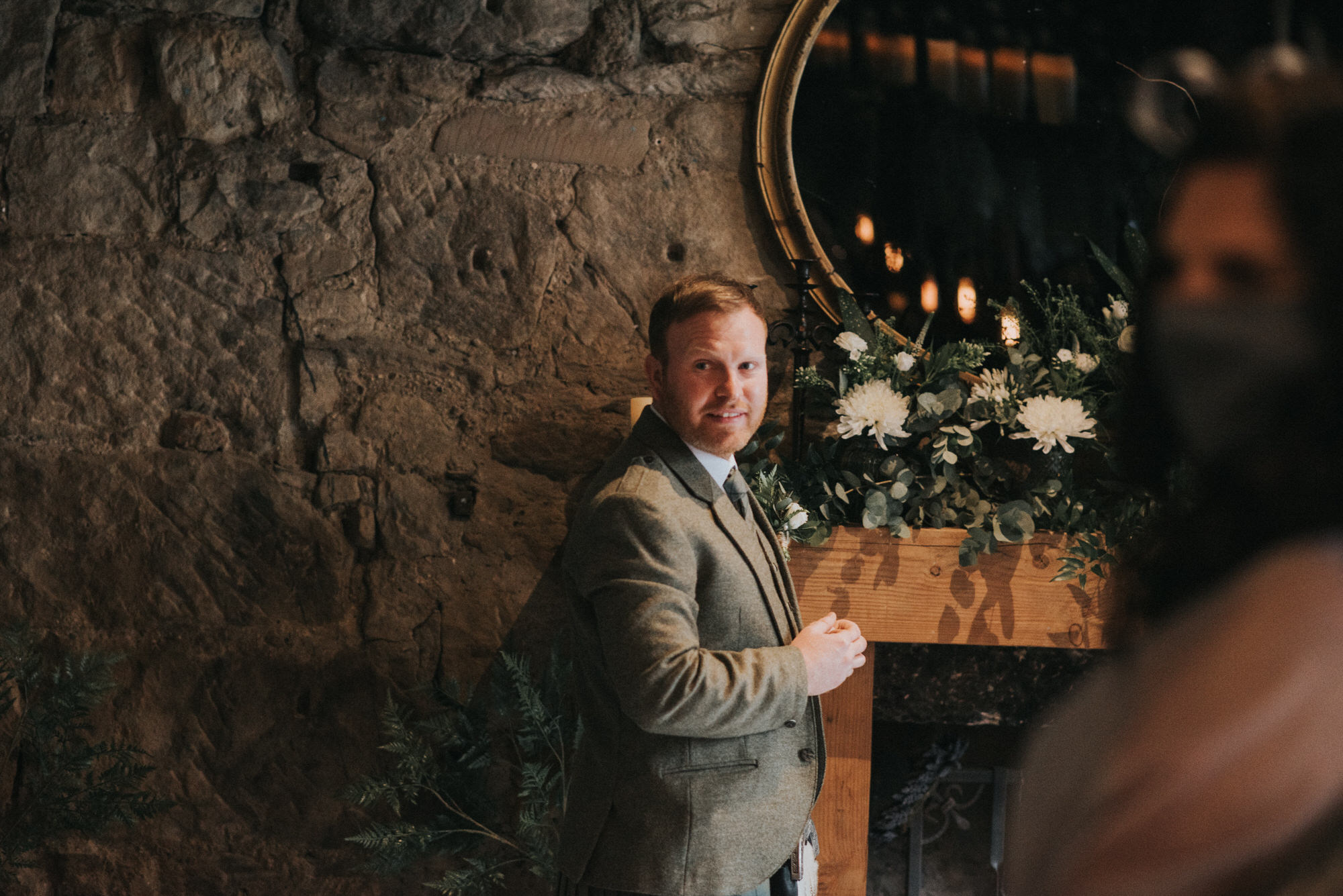 The groom looks over his shoulder  at The Bothy, Glasgow and smiles as he sees his bride for the first time