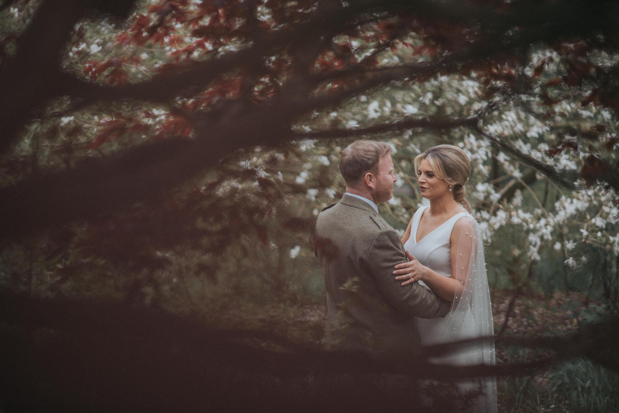The bride and groom are seen in amongst some trees