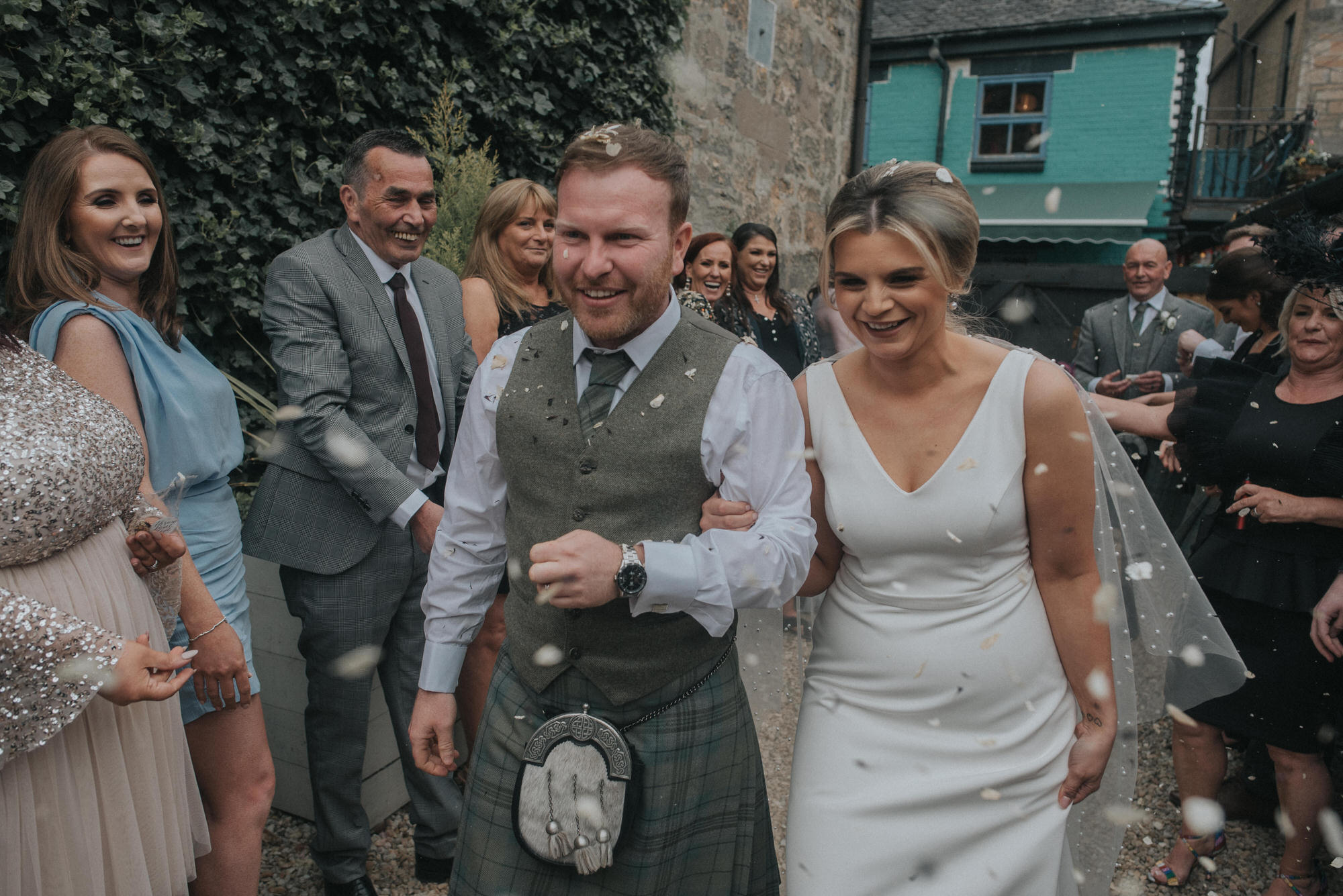 The bride and groom walk through a line of confetti at The Bothy