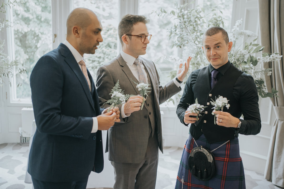The groomsmen look confused as they decide on who gets which buttonhole