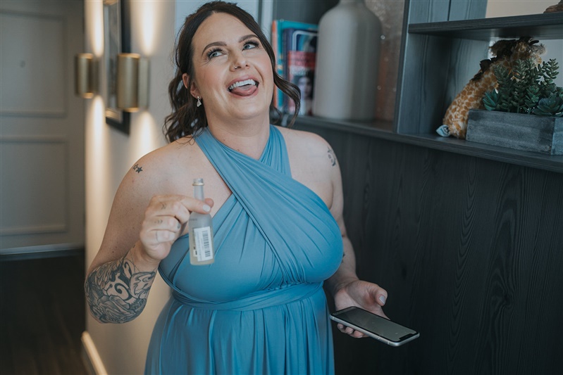 A bridesmaid makes a silly face with her tongue out as she drinks some Lemoncello