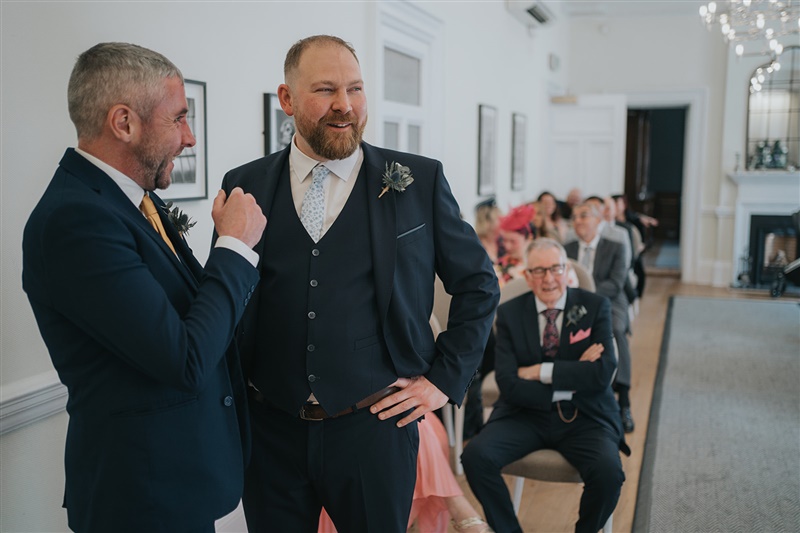 The groom and his best man share a laugh just before the bride is about to walk in the room