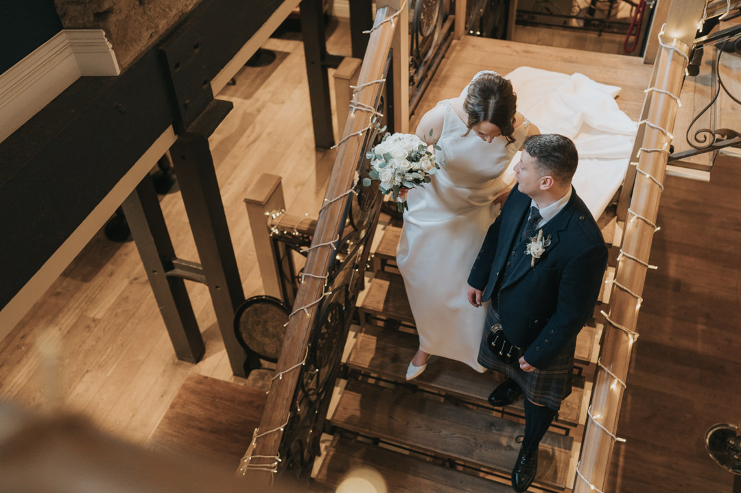 A bride and groom walk down the stairs of Citation Weddings & Events in Glasgow