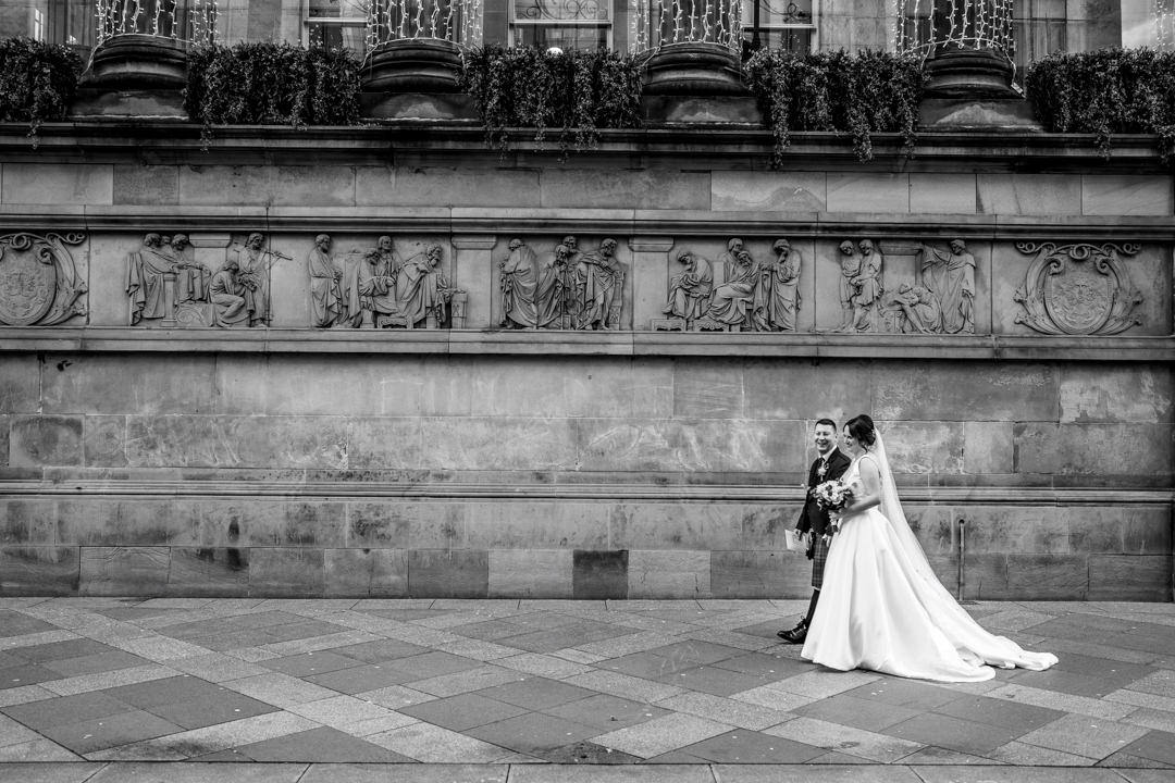 Black & White image of a bride and groom walking in front of Citation Weddings & Events in Glasgow