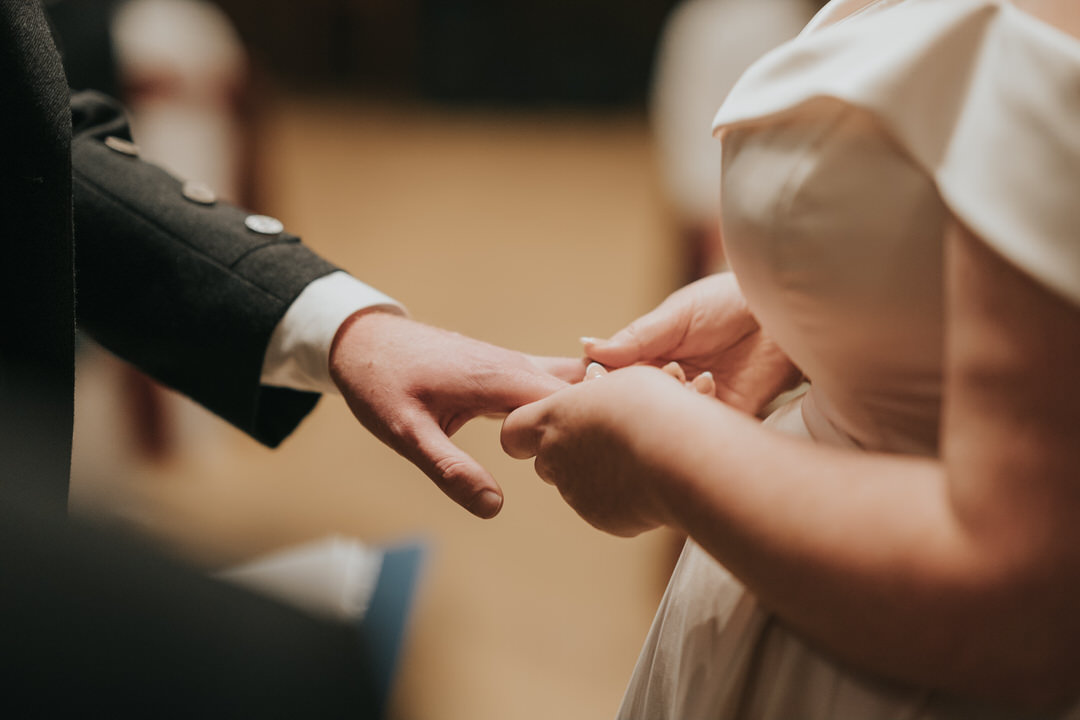 A close up of the bride and grooms hands exchanging rings at their wedding at the Trades Hall in Glasgow